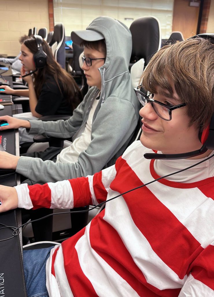 Image of three students sitting at computers wearing headsets