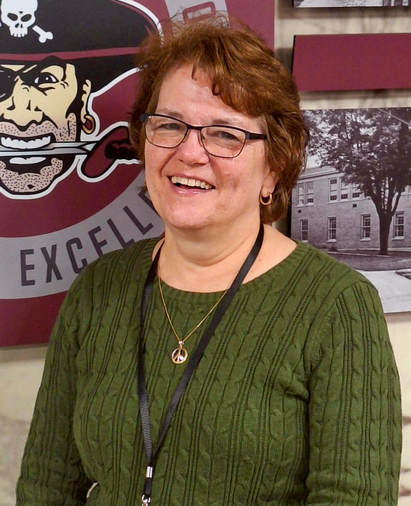 A woman wearing a green sweater smiling for a photo