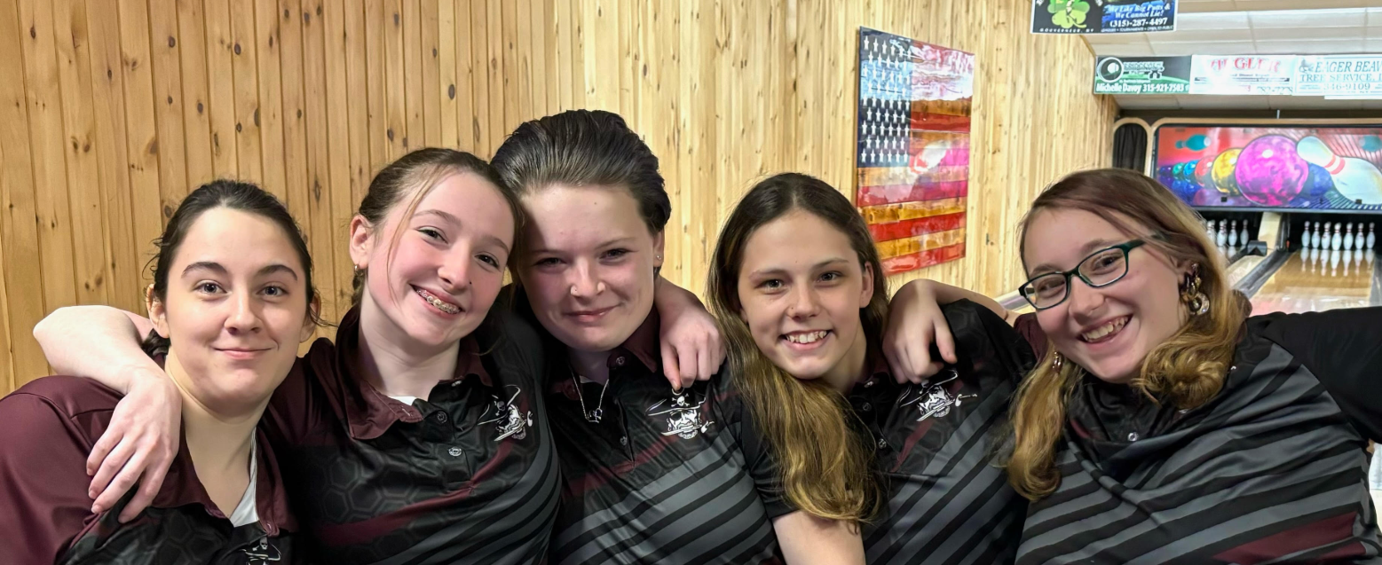 Five students pose for a photo together in a bowling alley